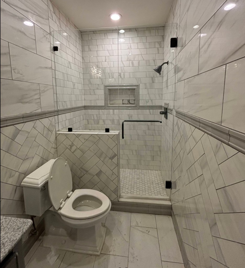 Bathroom with marble-look wall tile, herringbone pattern, and hex tile shower floor.