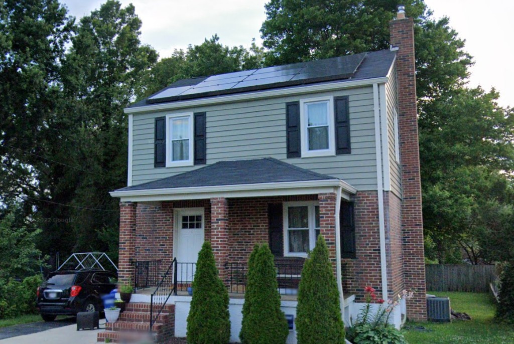 Two-story home with a dark shingle roof and solar panels.